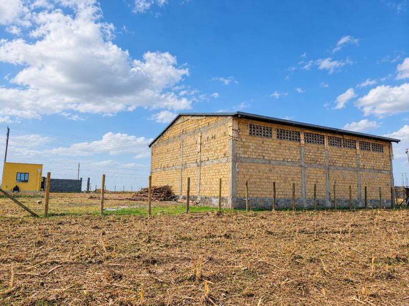 The Firstfield grain store at Olonini, a stone-block building with a steel roof, behind a new fence line under a blue sky