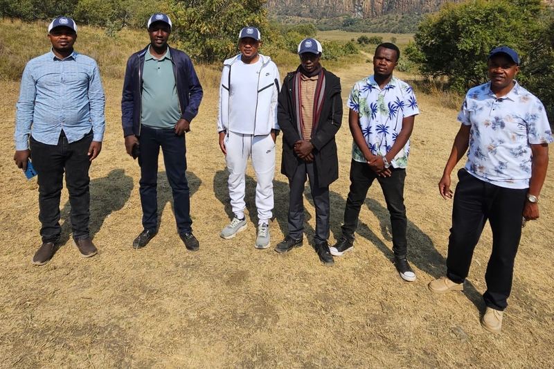 The Firstfield team standing together in open country, wearing Firstfield Farms caps